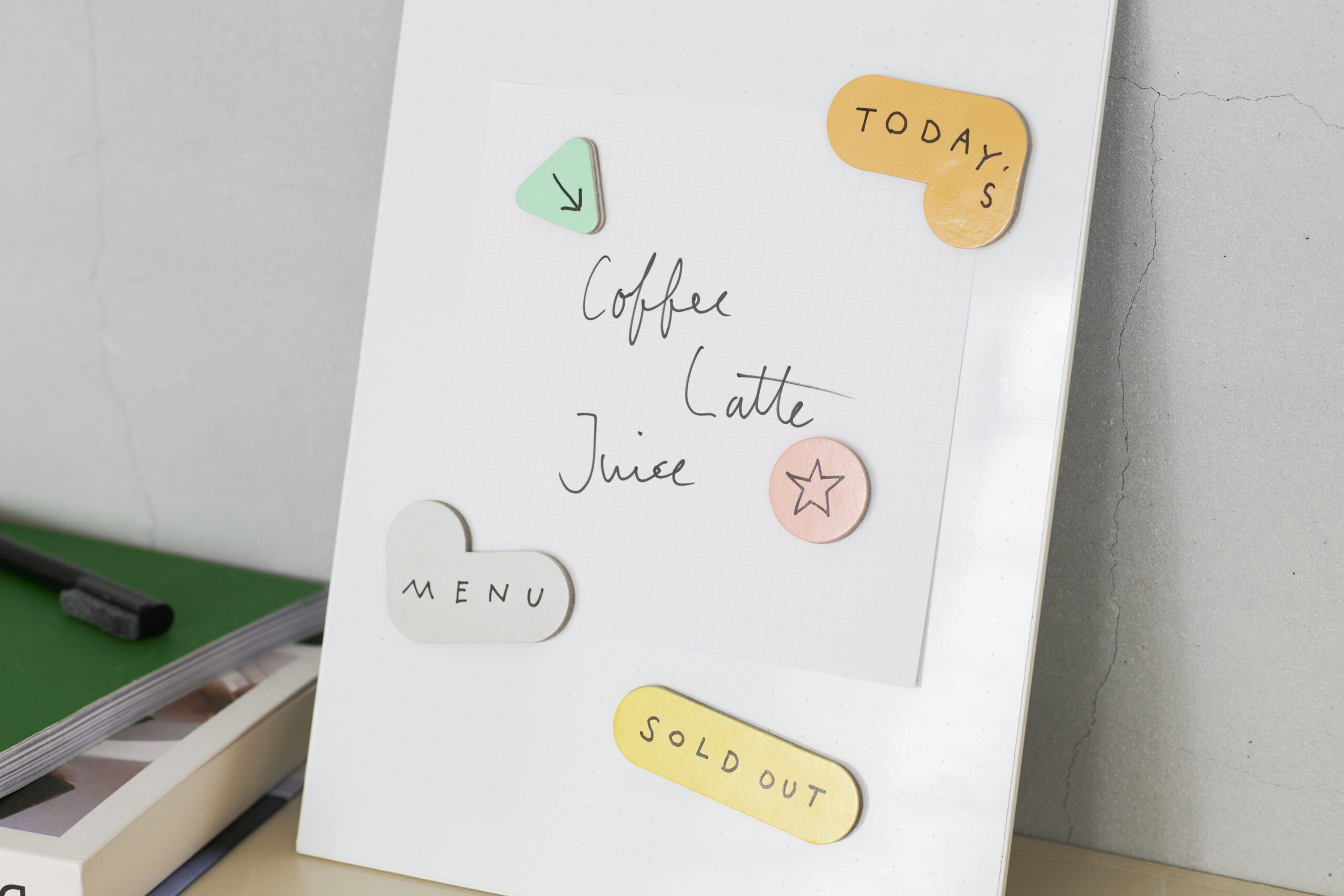White board with handwritten drink list (Coffee, Latte, Juice) and colorful circular tags, including a yellow 'SOLD OUT' label and 'MENU' button image in the corner.