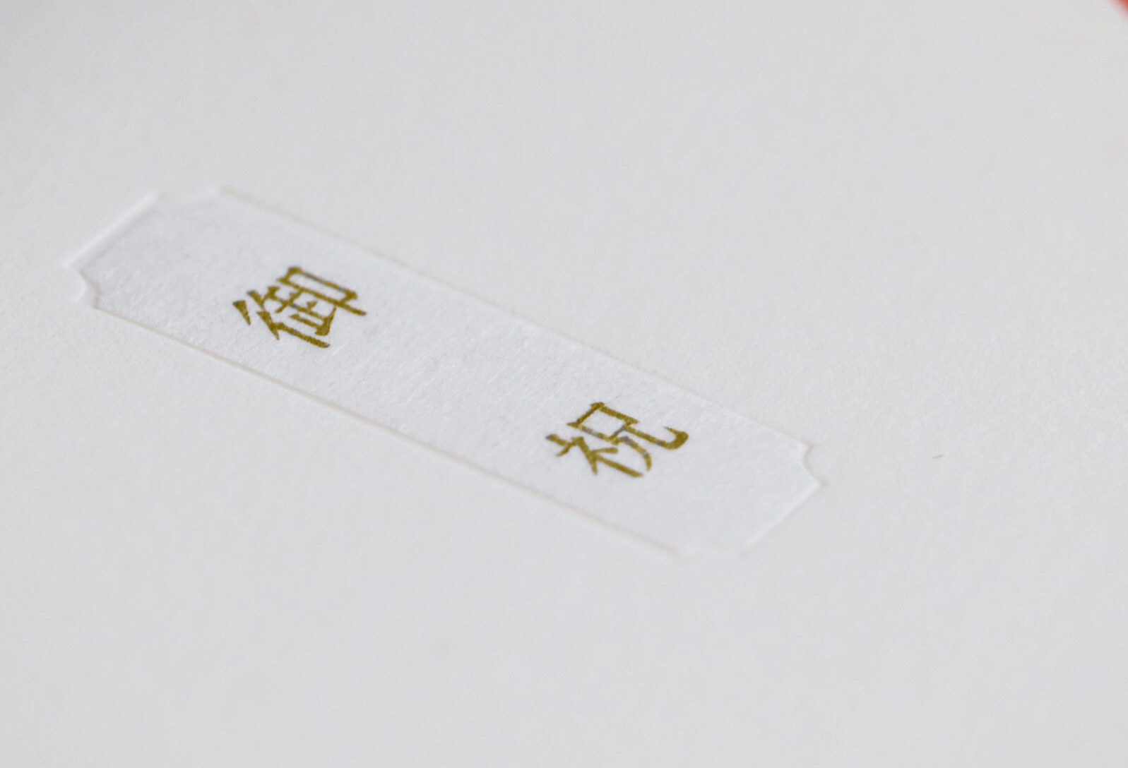 White tag on white background with gold-embossed Chinese characters 結婚 (marriage).