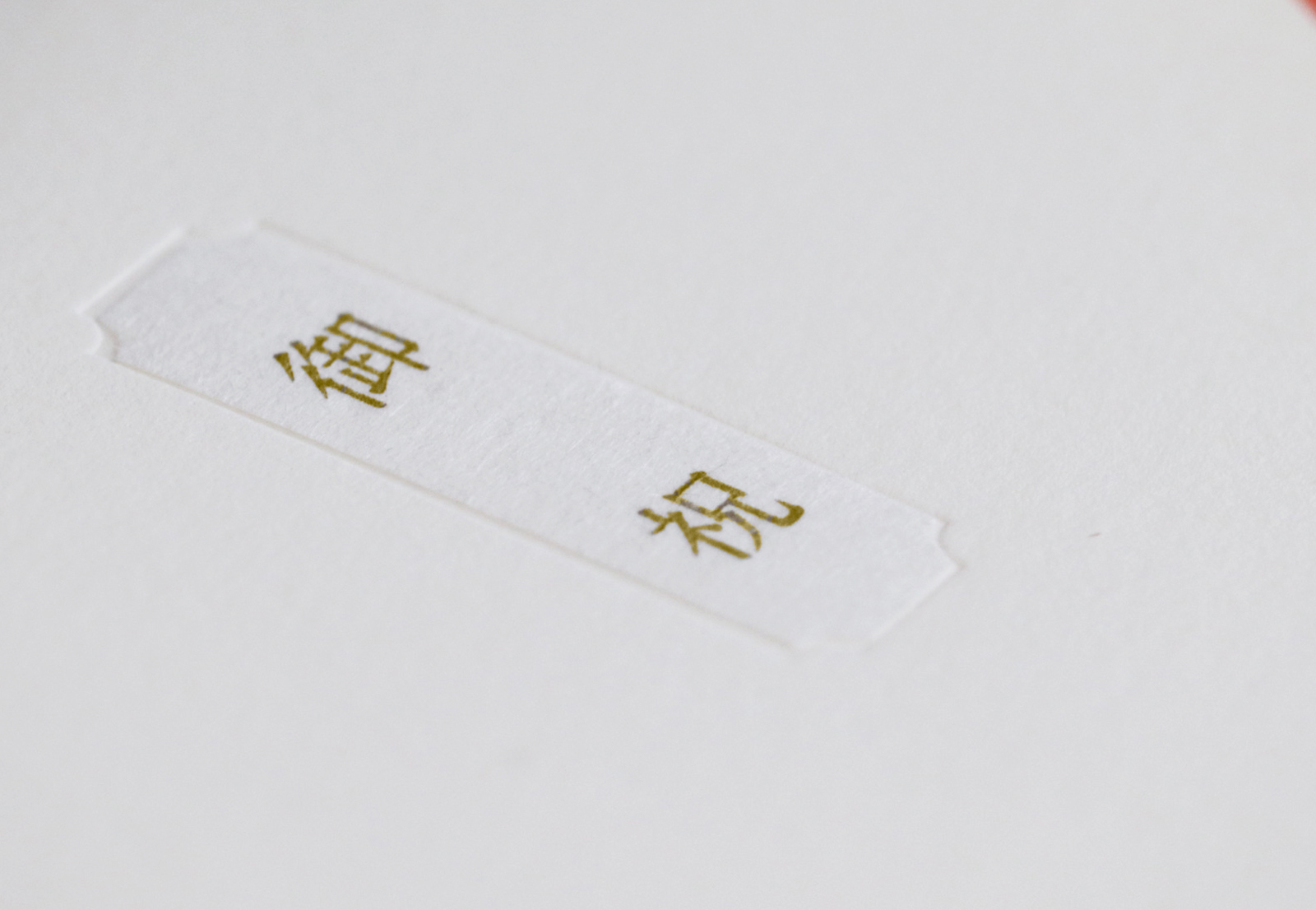 White tag on white background with gold-embossed Chinese characters 結婚 (marriage).