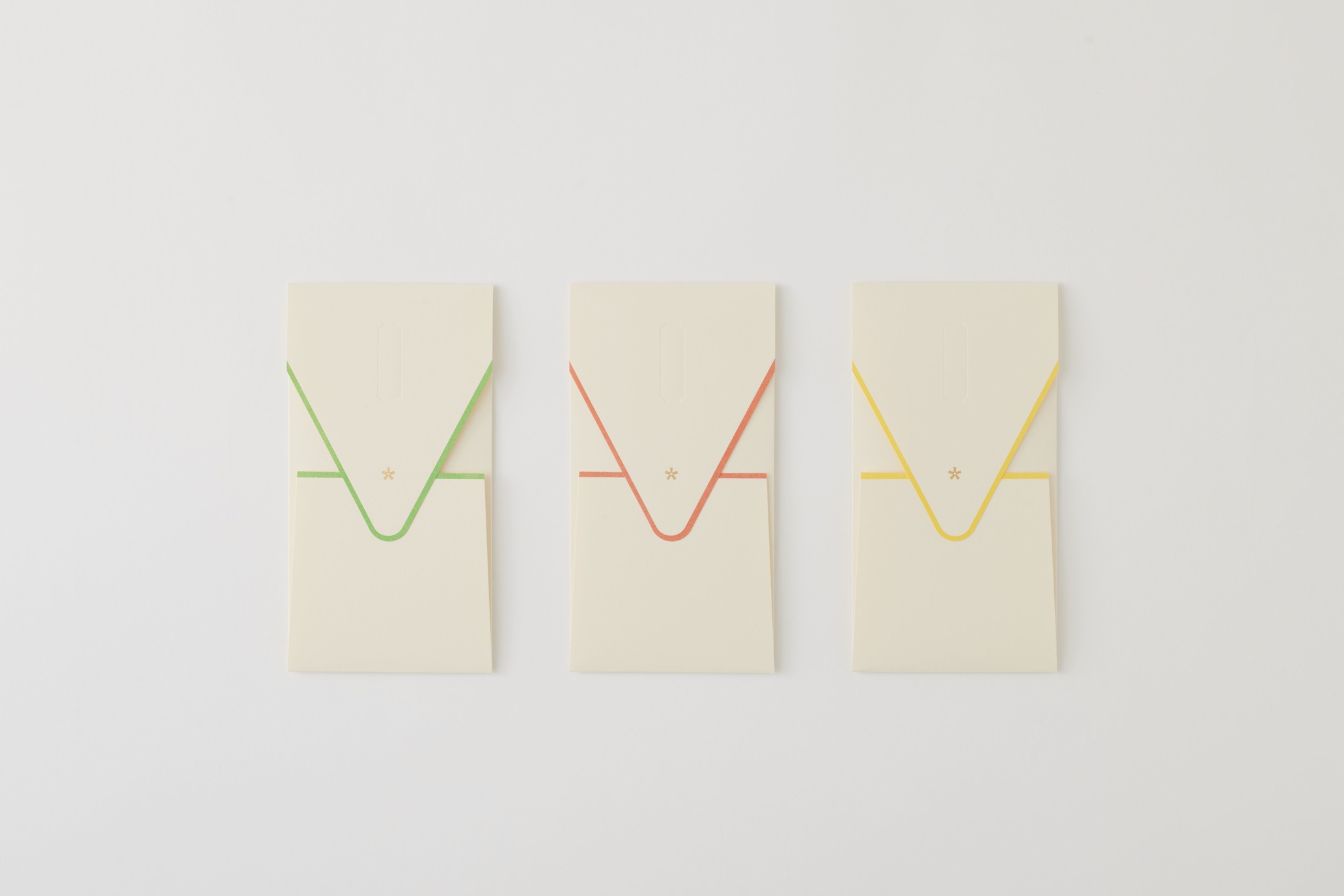 Three cream rectangular cards arranged in a row, each with a colored V-shaped ribbon (green, red, yellow) across the front.