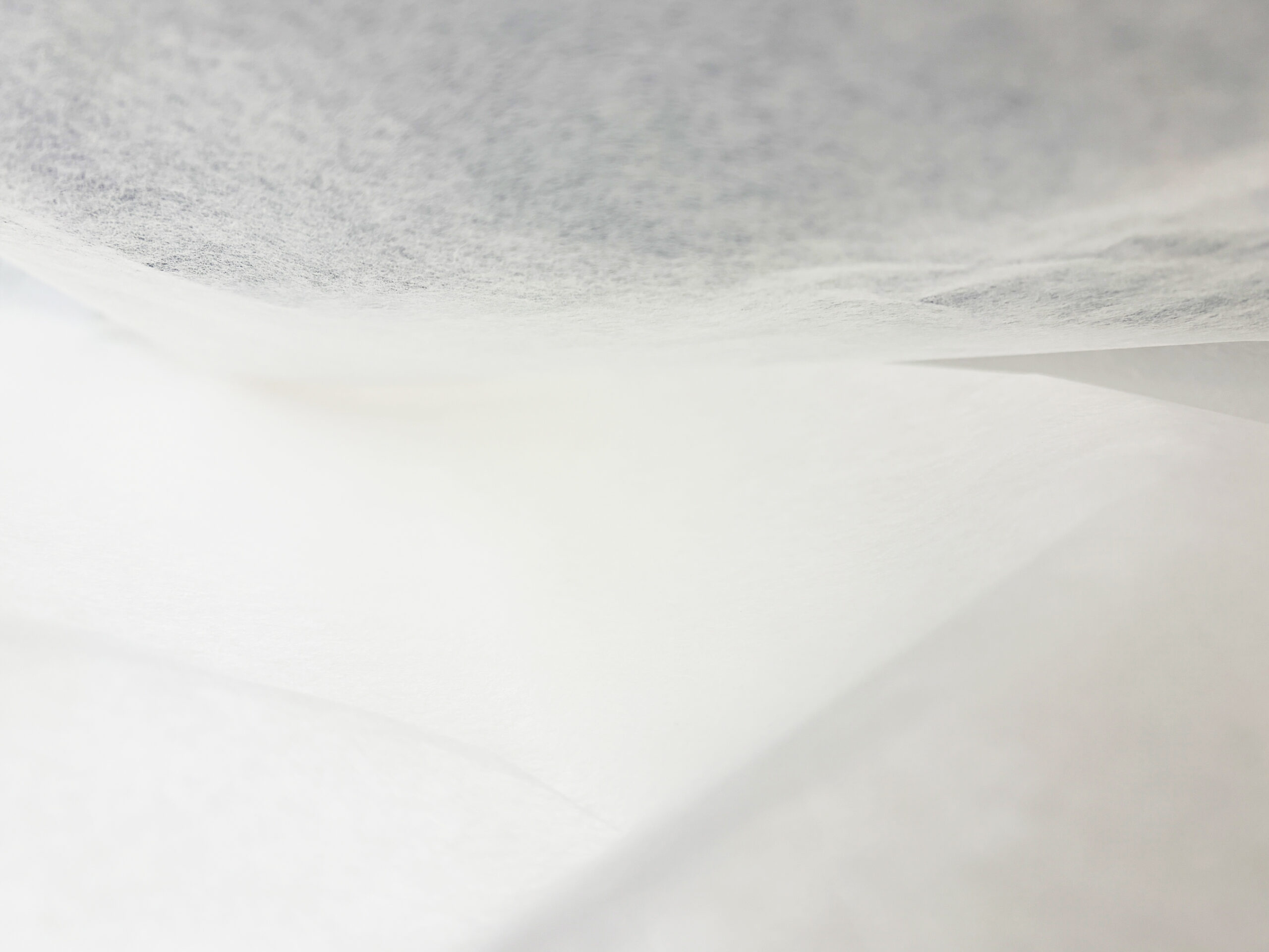 Close-up of a white bedsheet with soft shadows and folds in the fabric.